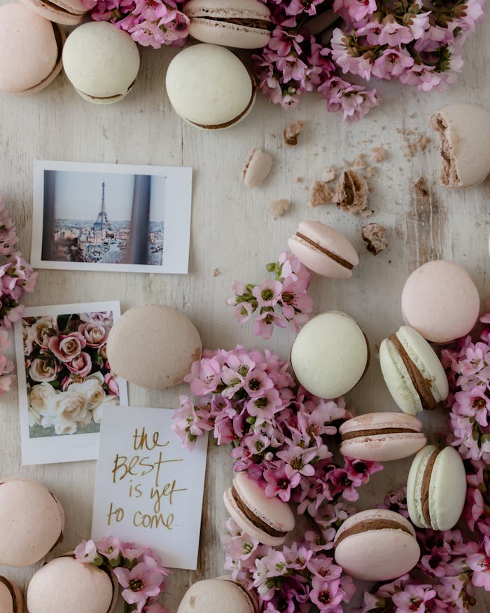 A flat lay of pastel macarons surrounded by pink flowers and inspirational photos.