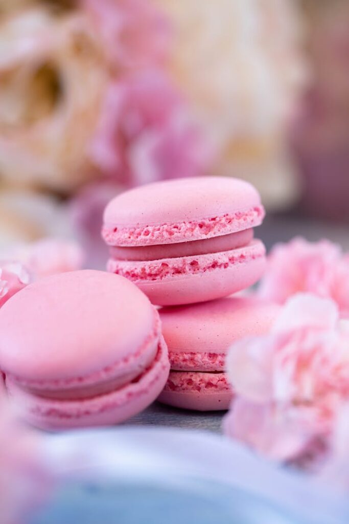 pexels-photo-7474292 Yummy sweet pink macaroons placed on table against fresh carnation flowers in daylight