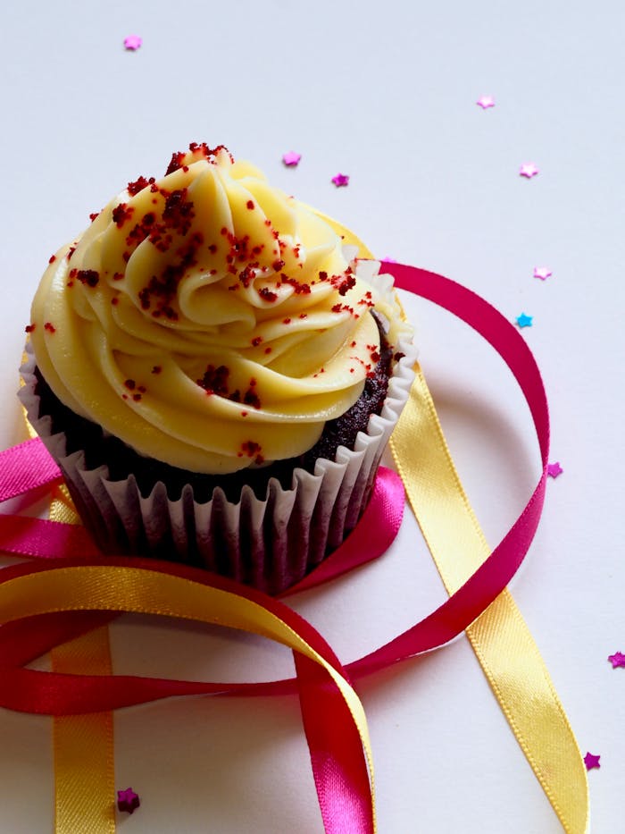 pexels-photo-913136 Tempting chocolate cupcake with creamy icing, adorned with colorful ribbons and confetti for a festive celebration.